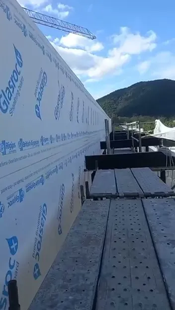 Andaime ao longo da fachada em steel frame com a grua ao fundo