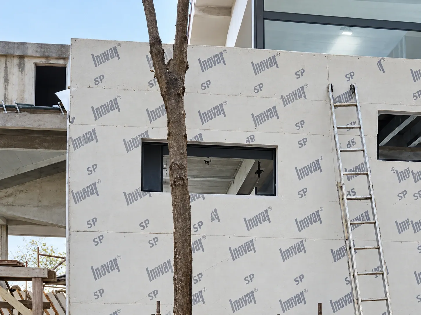 Volume da casa em steel frame fechado com placas e aberturas de janela, entre as árvores de um terreno de mata em Florianópolis