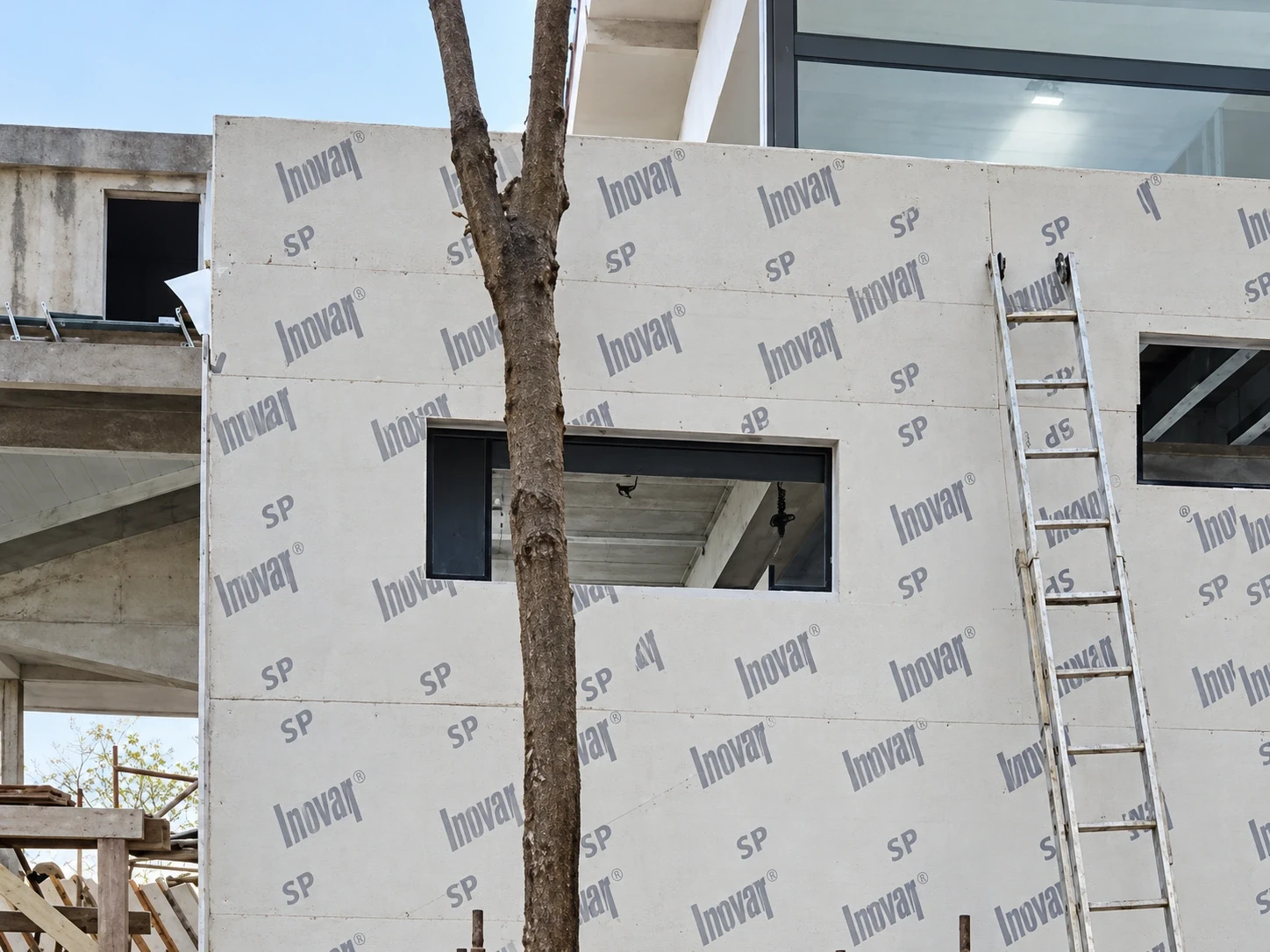 Volume da casa em steel frame fechado com placas e aberturas de janela, entre as árvores de um terreno de mata em Florianópolis