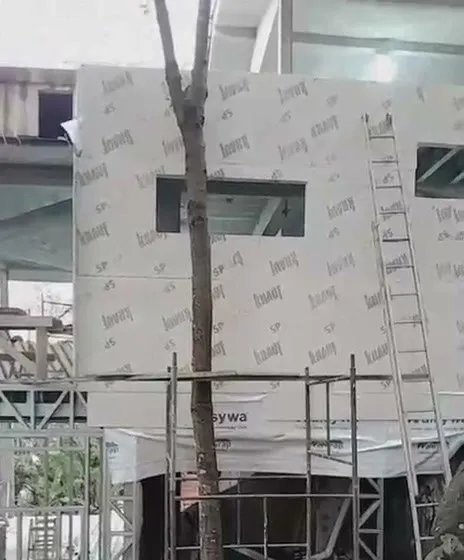 Volume superior da casa em steel frame com fechamento em placas e membrana entre as árvores