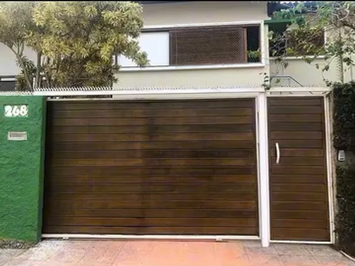 Fachada com muro pintado de verde e portão de madeira tratado com Osmocolor