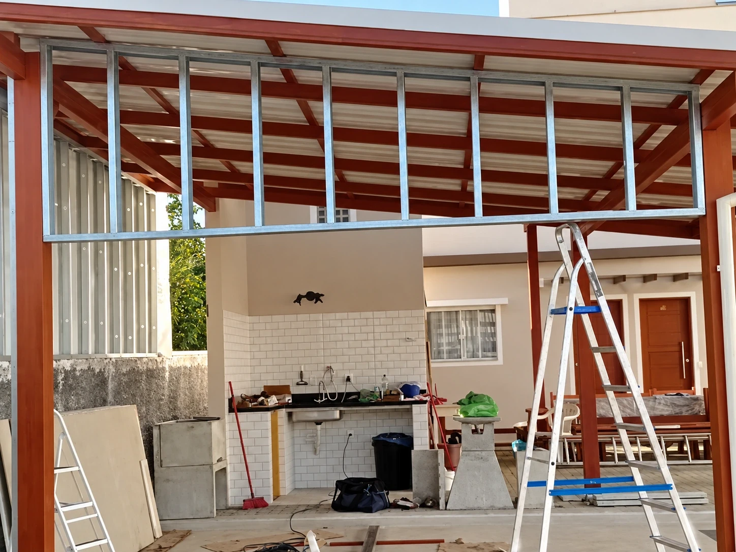 Estrutura de steel frame com montantes de aço galvanizado montada entre as vigas de um pergolado de madeira no Rio Vermelho