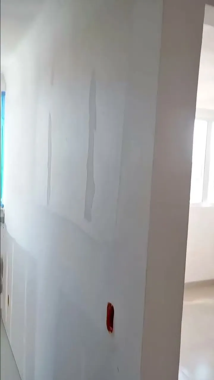 Parede de drywall com juntas tratadas ao lado de abertura de porta