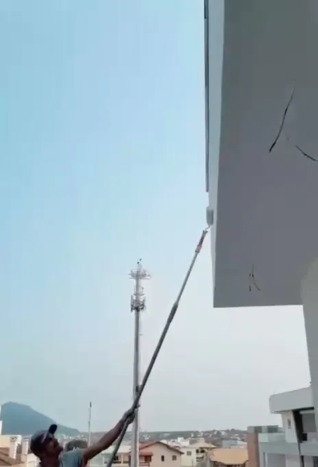 Pintor usando rolo de extensão no beiral de casa de alto padrão