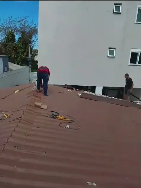Telhado metálico em instalação ao lado de prédio residencial