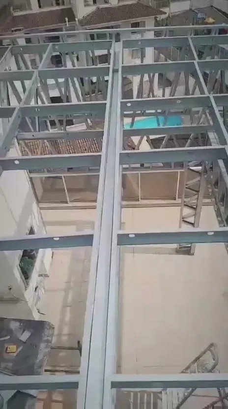 Vigas de steel frame sobre o terraço com a piscina do prédio ao fundo