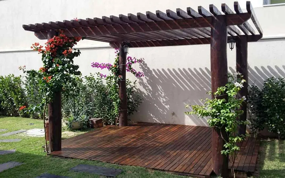 Pergolado e deck de madeira em jardim com flores e vegetação